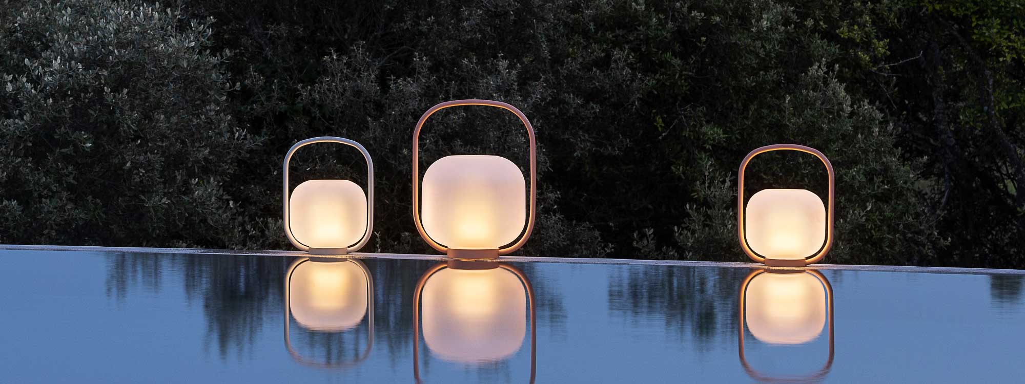 Image of Todus Otus outdoor lanterns on poolside at dusk, with their reflection shown in the water