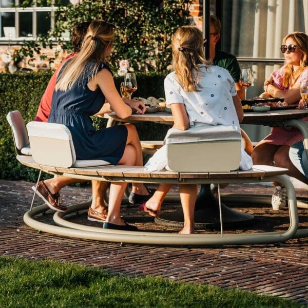 Image of people sat on Wünder's The Seat, shown on top of The Circle round picnic table and benches