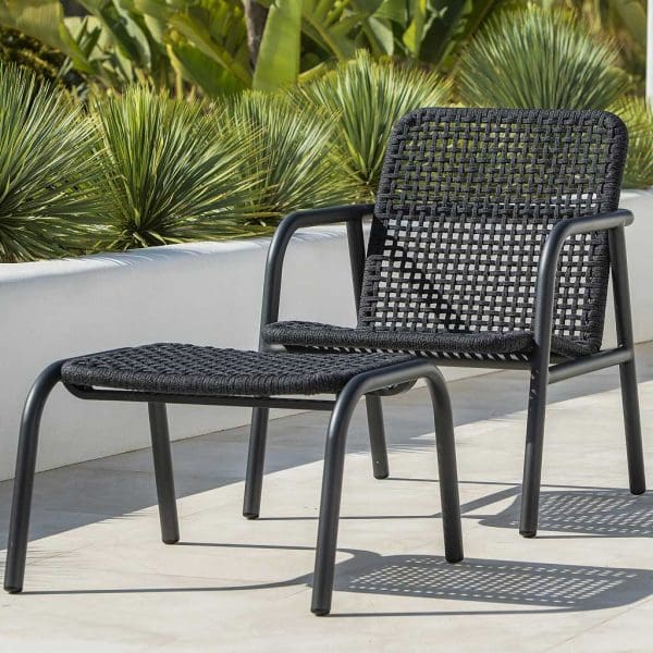 Image of Durham modern aluminium garden lounge chair and foot stool in charcoal colour finish, with Polyolefin rope seat and back, shown on a sunny terrace with exotic plants in background