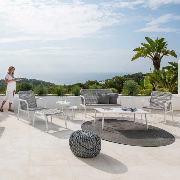 Image of white Durham garden lounge sofa and chairs on sunny terrace with exotic plants and blue sky in the background