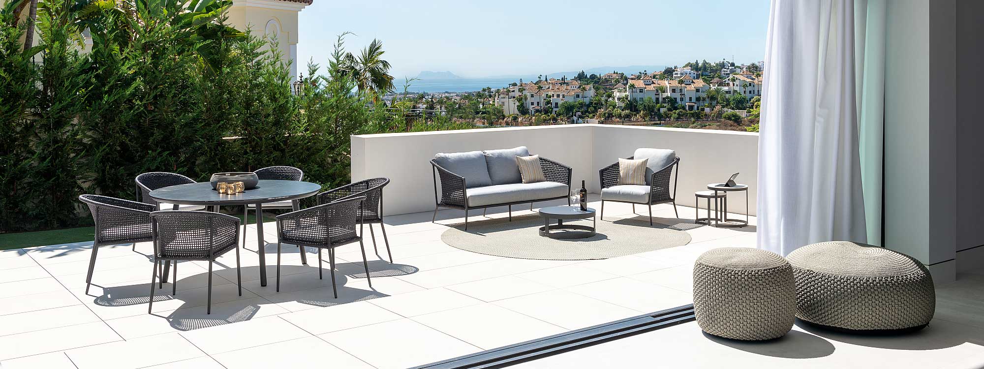Image of Durham circular garden table with Jati & Kebon furniture, shown on a Spanish terrace with rooftops, sea and Gibraltar in the background