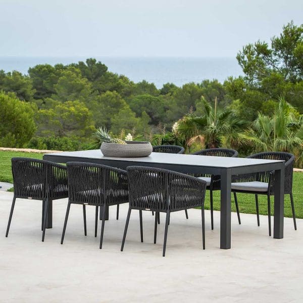 Image of Fortuna Rope black tub garden chairs around Lugo black garden table on terrace with woodland and hills in the background