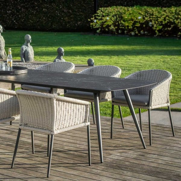 Image of Amazone ceramic garden table and Fortuna Rope dining chairs on terrace with lawn and sculptures in the background