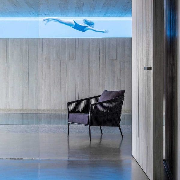 Image of Fortuna Rope modern black garden chair with woman swimming visible though glass-sided swimming pool in the background