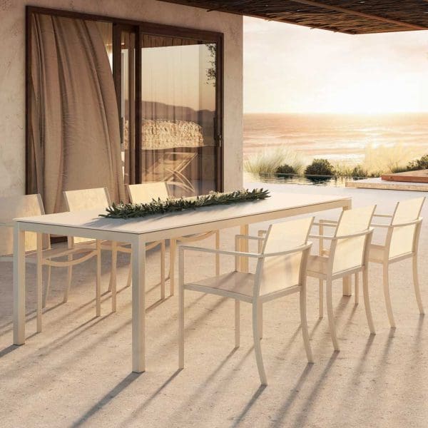 Image of white Ozon garden chairs and Taboela outdoor dining table on terrace in late afternoon sun