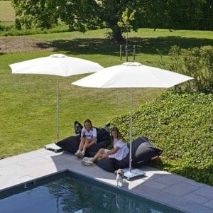 Image of couple of girls sat on beanbags on poolside beneath Prostor P50 small centre mast parasols