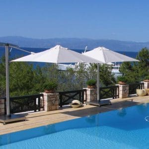 Image of Prostor P6 cantilever parasols with white canopies along sunny poolside with blue sea and sky in the background
