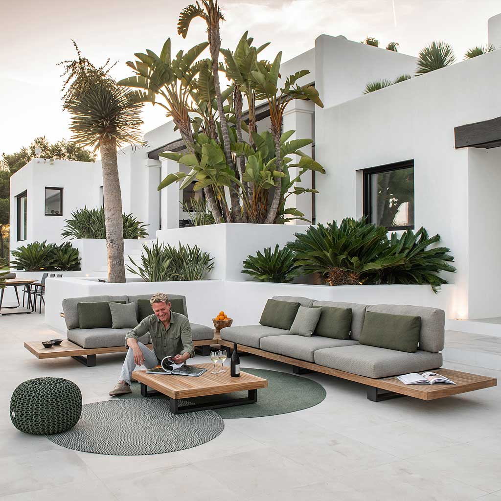 Image of man relaxing on terrace at dusk with Jati Kebon Truro modern teak sofa in the background