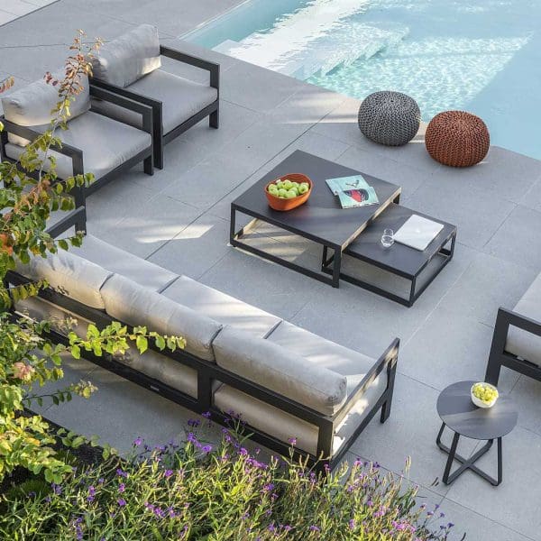 Image of aerial view of Vigo XL contemporary garden sofas and lounge chairs in charcoal finish and grey cushions, shown in late afternoon shade around the poolside