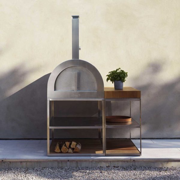 Image of Roshults stainless steel pizza oven stood next to outdoor kitchen unit with FSC teak chopping block