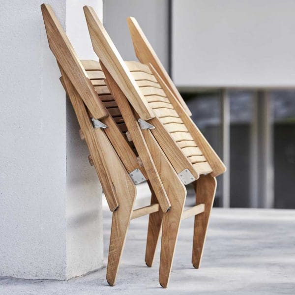 Image of pair of folded Flip teak recliner chairs by Cane-line, shown leaning against a wall