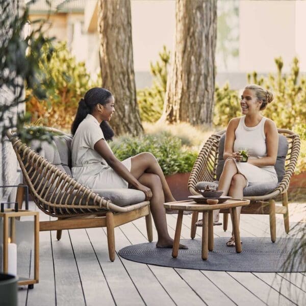 Image of women relaxing in Caneline Strington outdoor lounge next to Royal Teak coffee table