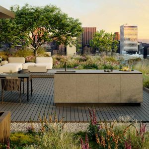 Image of Oiside OiCook modern garden kitchen surrounded by lush planting, with high rise buildings and rooftops in the background