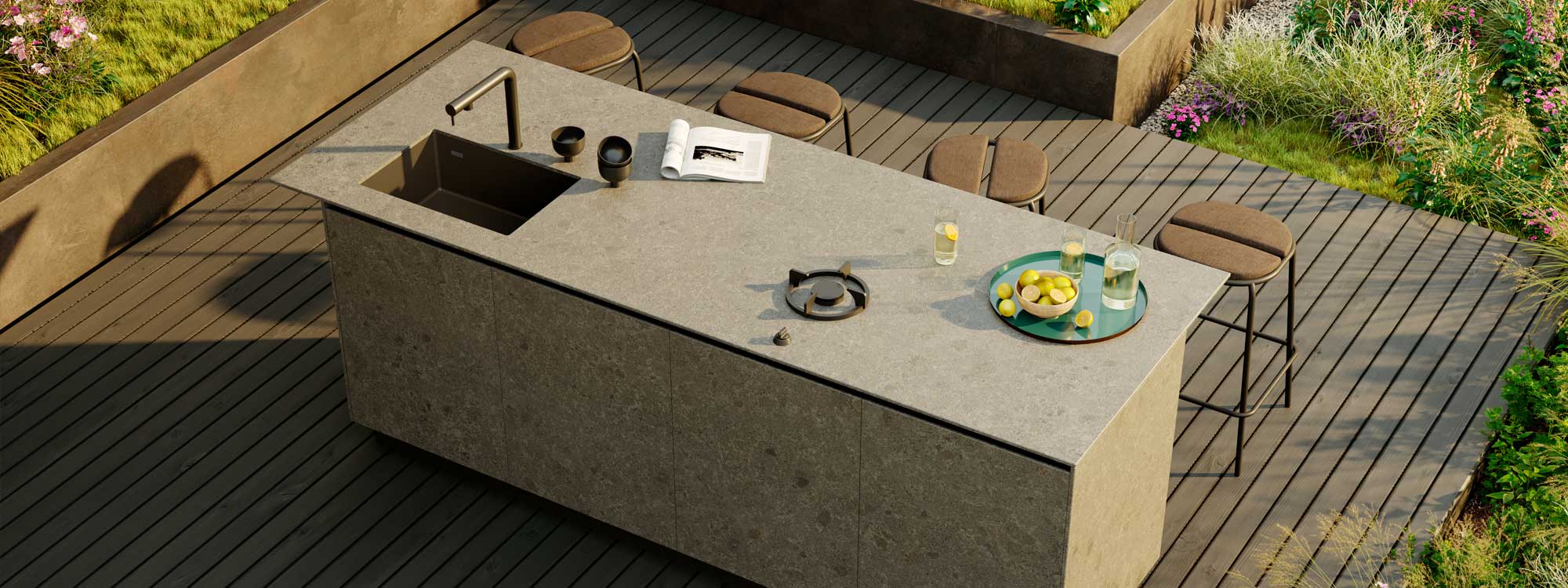 Image of OicCook ceramic outdoor kitchen island with sink and gas hob, with Parc stools next to countertop surface