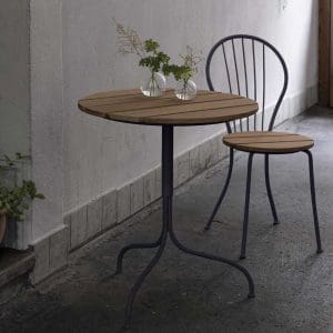 Image of Akleja compact garden table and chair by Grythyttan Stålmöbler, with 2 small circular glass vases on the table top