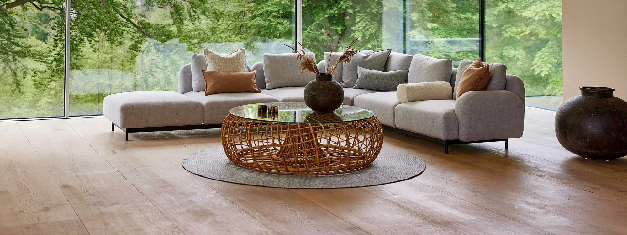 Image of Aura large corner sofa with upholstery in Light-Grey Cane-line Ambiance, with Nest natural rattan coffee table in the centre