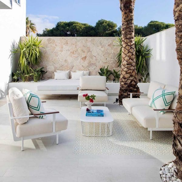 Image of intimate white-washed terrace palm trees and exotic plants, together with white Penda garden sofas and white Panama low table by Oiside Spain