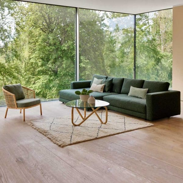 Image of Scale modern sectional sofa and daybed in Dark-green Cane-line Zen fabric, with wave cane coffee table and Moments cane lounge chair in the foreground