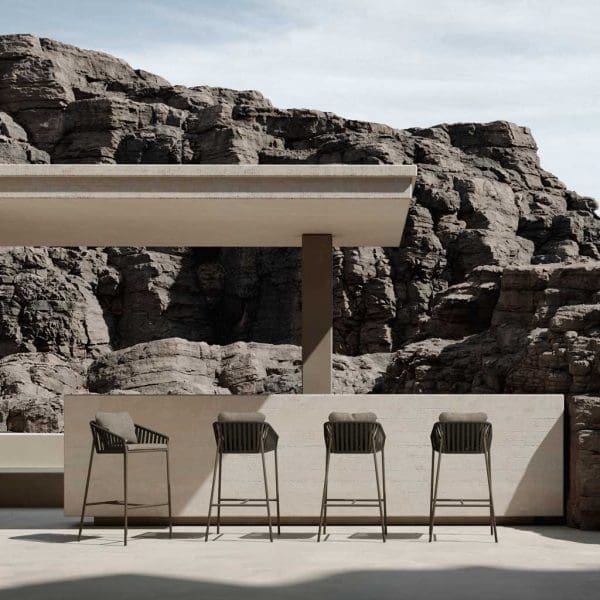 Image of Oiside Twist contemporary bar stools shown a a minimalist outdoor bar, with rockface in the background