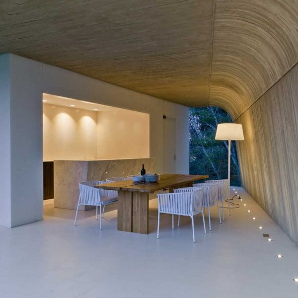 Image of Oiside Twist white garden chairs next to large wooden garden table, beneath poured concrete ceiling