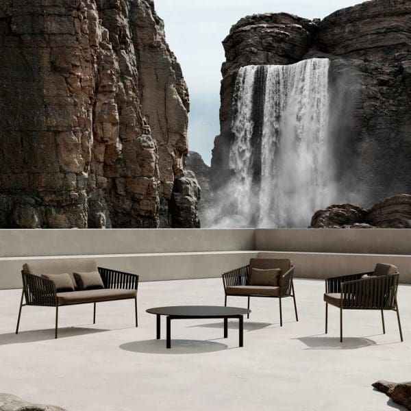 Image of Oiside Twist modern 2 seat sofa and outdoor lounge chairs on a sunny terrace, with rockface and waterfall in the background