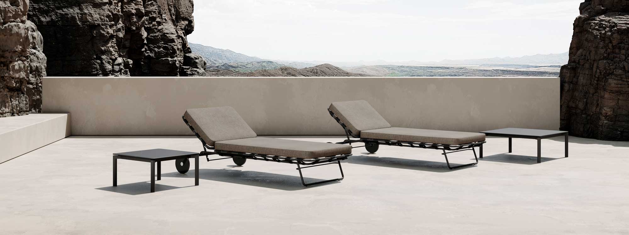 Image of pair of Twist contemporary sun loungers by Oiside, shown on sunny terrace with arid countryside in the background
