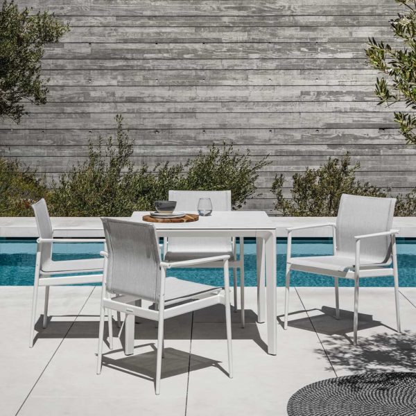 Image of 180 modern white garden armchairs and Carver modern square dining table by Gloster, shown on sunny poolside