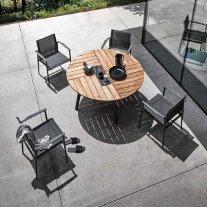 Image of Meteor-coloured 180 stacking garden chairs around round teak dining table by Gloster