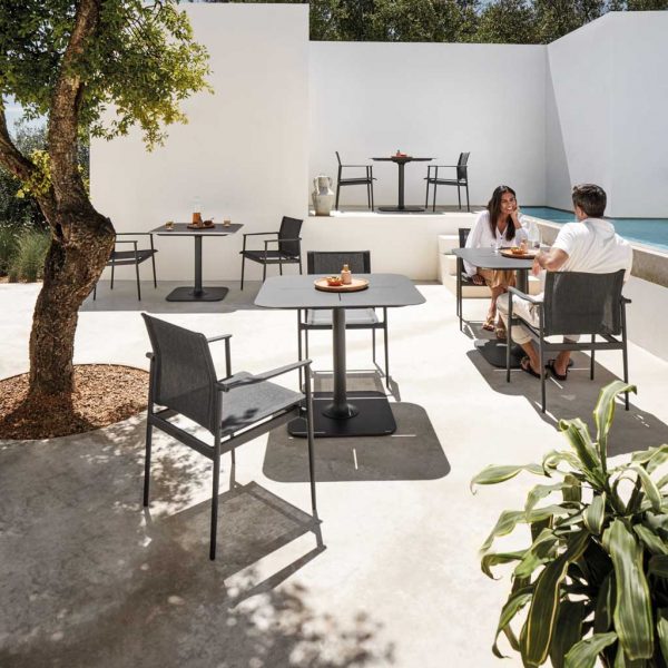 Image of 180 contemporary garden armchairs and Grid black bistro tables by Gloster in sun and shade of whitewashed courtyard