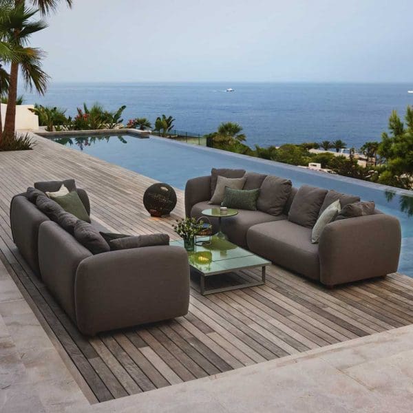 Image of pair of Capture long garden sofas on poolside with coastline in the background