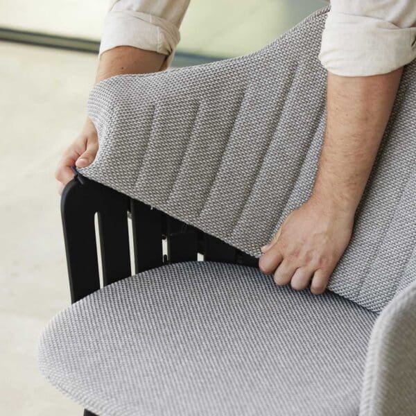 Image of man demonstrating how easy it is to fit Cane-line Choice bar stool's back upholstery