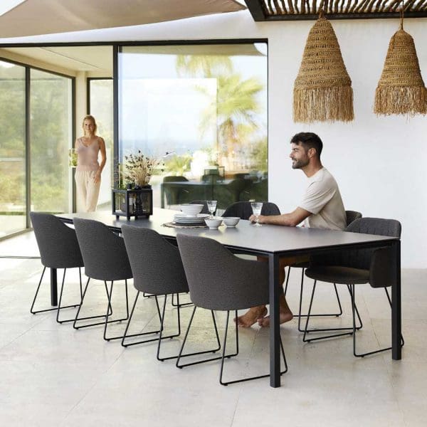 Image of smiling man with beard sat in Choice contemporary garden chair next to Pure minimalist dining table by Cane-line