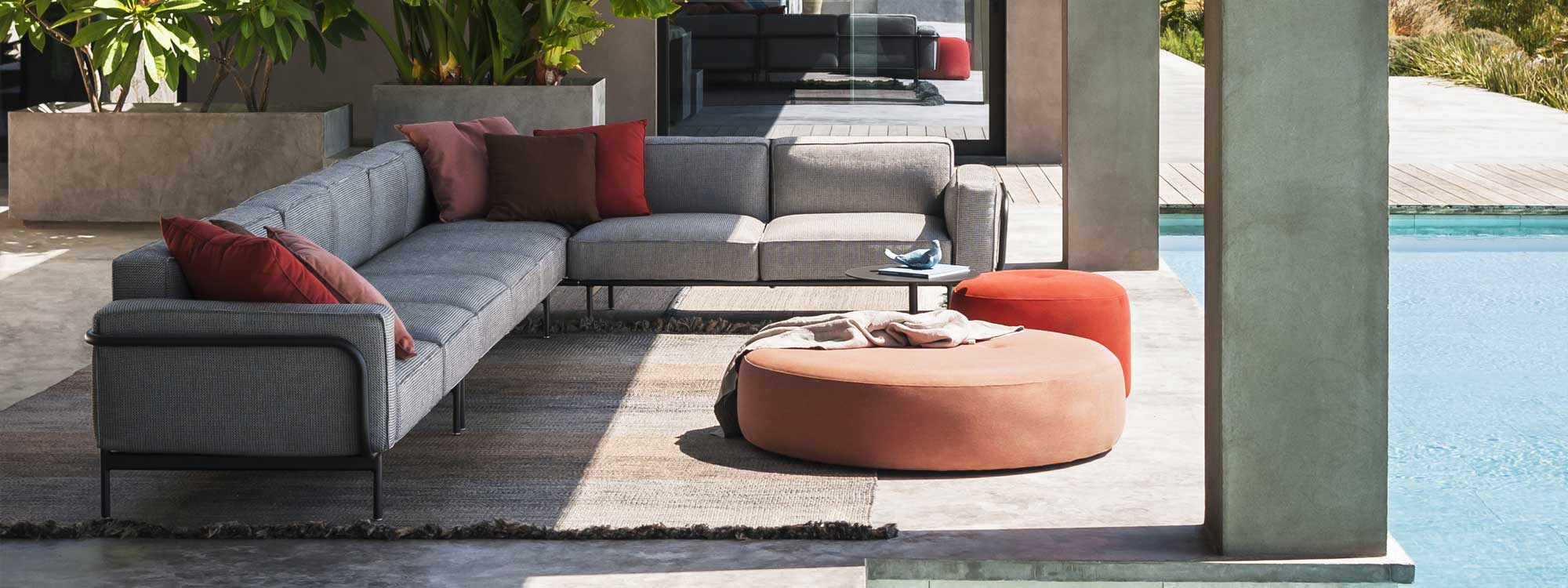 Image of RODA contemporary garden corner sofa with black tubular frame and grey cushions, together with pair of Double round garden poufs