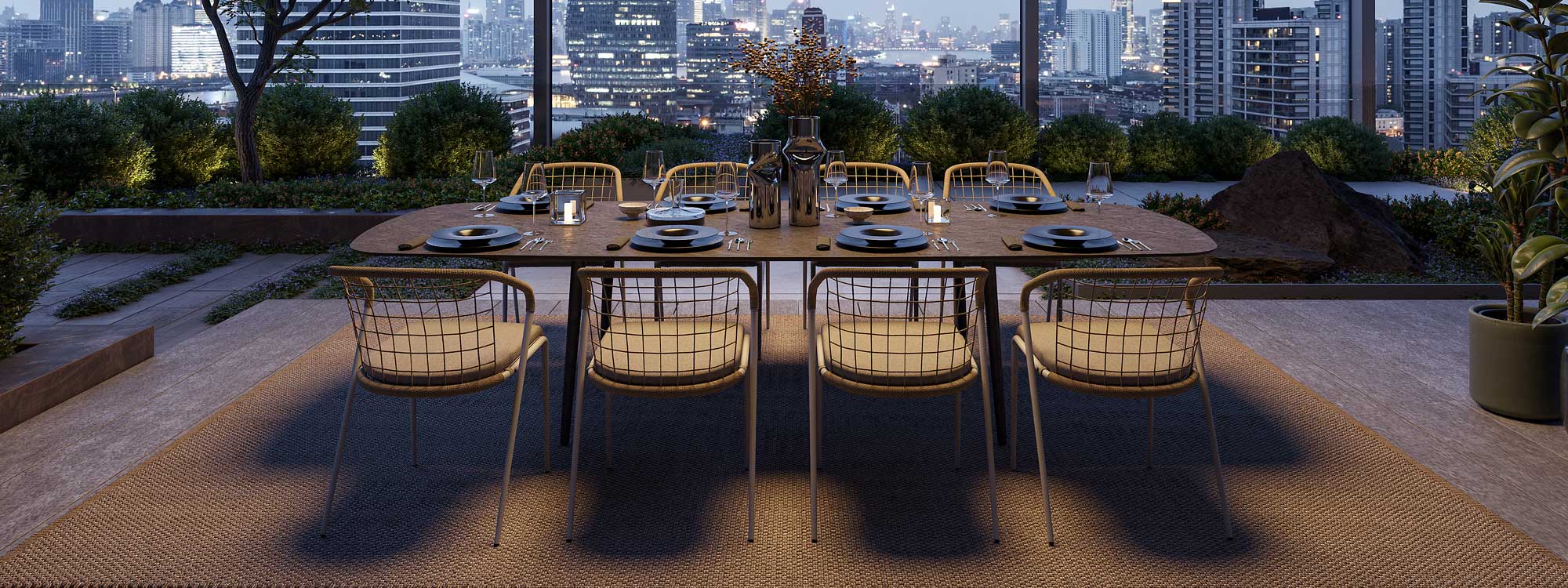 Image at dusk of rooftop terrace with Royal Botania Styletto dining table and Fensi chairs, with twinkling lights of city skyline in the background