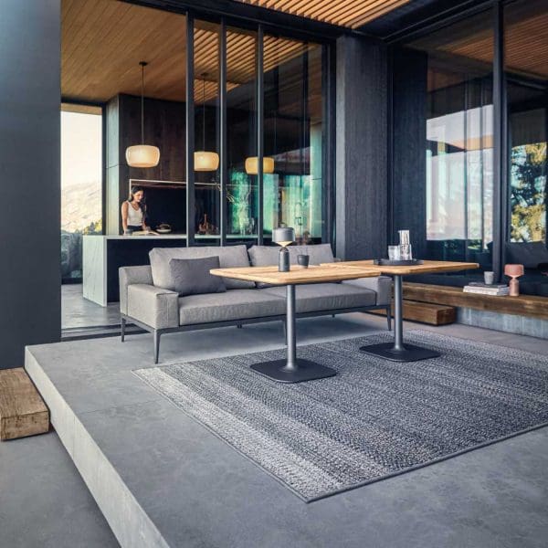Image of Gloster Grid outdoor dining sofa and tables beneath cantilevered terrace ceiling