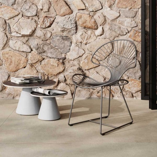 Image of Ostrea modern garden chair next to pair of Conix concrete side tables by Royal Botania on sunny terrace