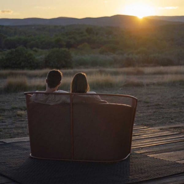 Image of back of Slide 2 seater garden sofa by Todus with couple sat inside watching the sunset