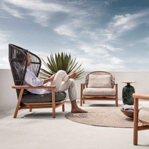 Image of man relaxing in dark grey Fern outdoor lounge chair with teak base by Gloster