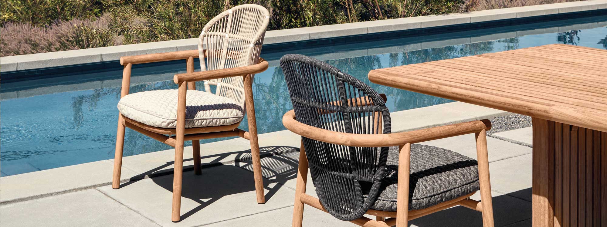 Image of pair of Gloster Fern teak garden chairs and Deck modern teak table on sunny poolside terrace