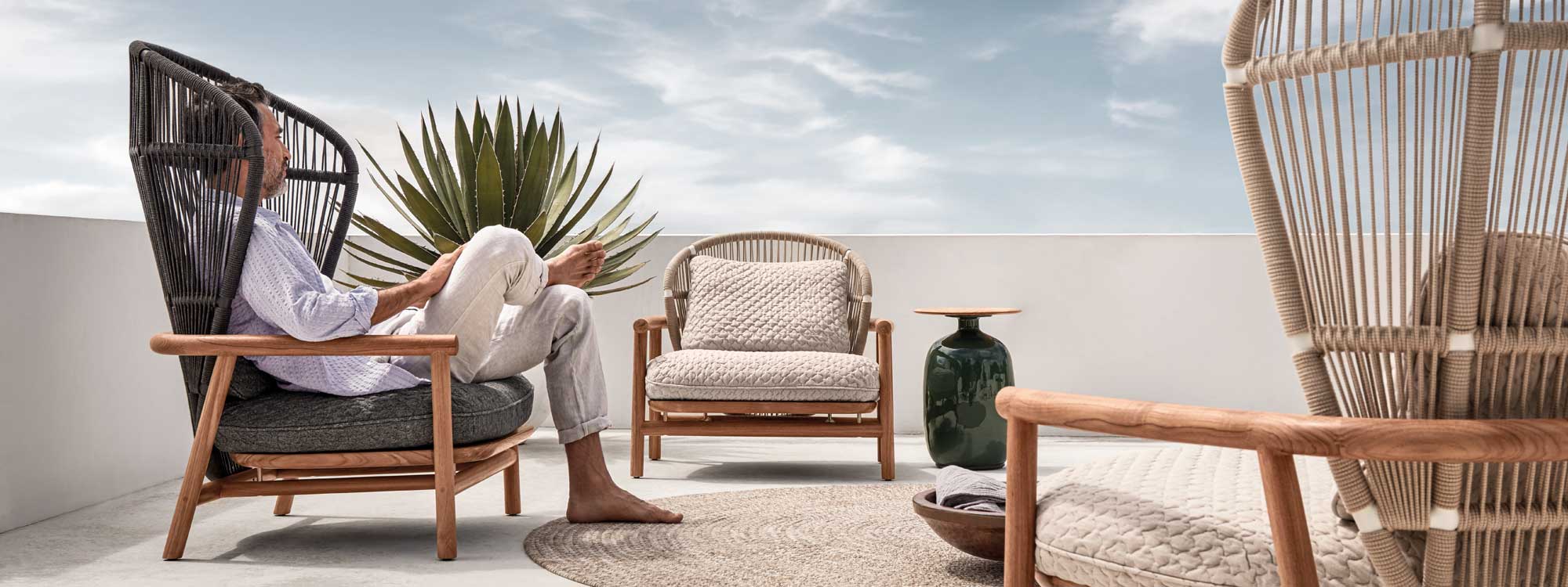 Image of man dressed in white relaxing in Grey Fern garden easy chair with high back by Gloster