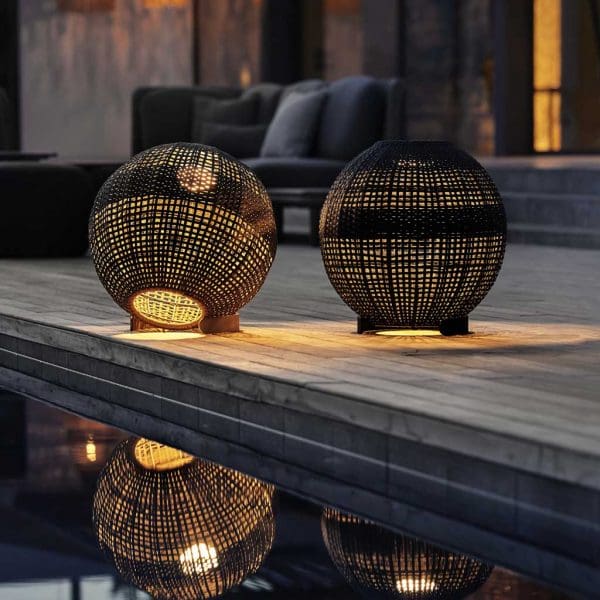 Image of pair of Cane-line Illusion spherical solar lanterns casting reflection of light and shade into waters of swimming pool to the side