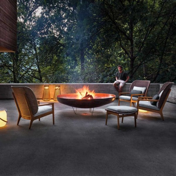 Image of Gloster Kay luxury garden furniture placed around the roaring flames within a circular fire pit