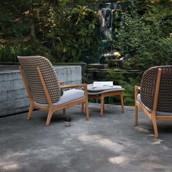 Image of rear of Kay high-backed garden lounge chair and footrest by Gloster, on terrace at dusk