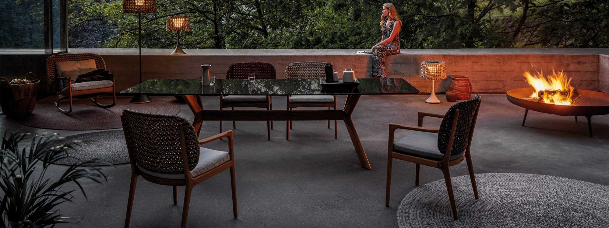 Image at dusk of Gloster Kay outdoor chairs on terrace, with flaming circular fire pit to the side.
