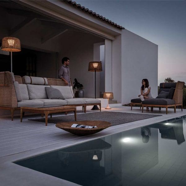 Image at dusk of Lima modern wicker garden sofa and illuminated Mesh exterior standard lamps by Gloster