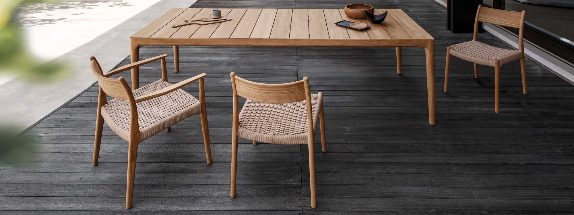 Image of Gloster Lima teak dining furniture with elegant hand-woven wicker seats