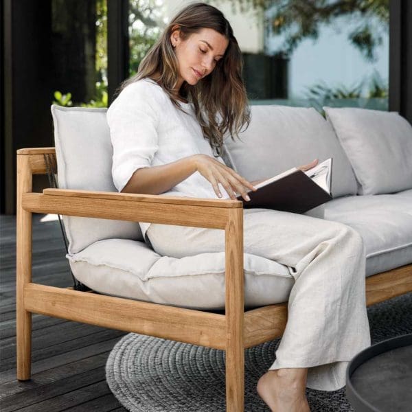 Image of woman sat in Saranac contemporary teak garden sofa by Gloster