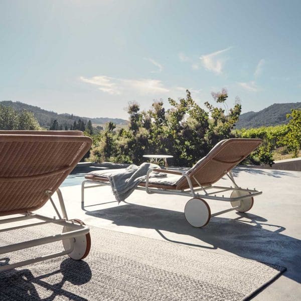 Image of Fresco modern sun beds by Gloster on sunny poolside terrace with undulating green hills in the background