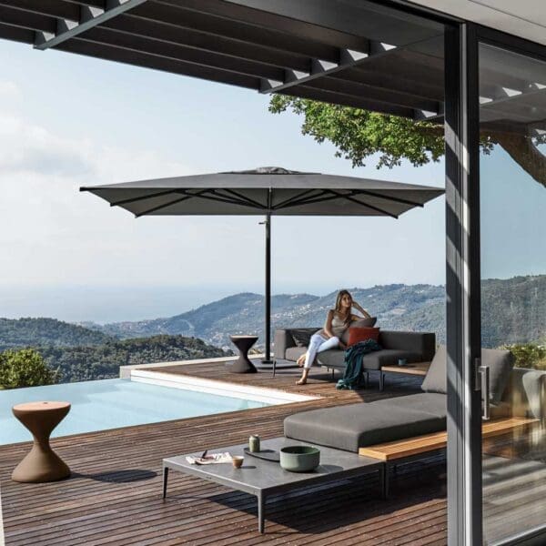 Image of woman sat in the shade of Halo large cantilever parasol by Gloster