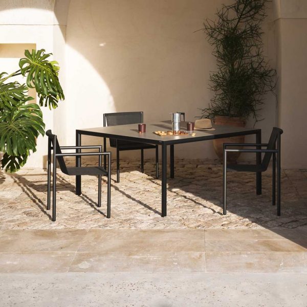 Image of anthracite coloured Plein Air contemporary garden dining set by RODA in sun and shade of rustic courtyard